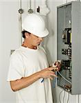 An electrician trimming wire as he hooks up an electrical panel.  Model is an actual electrician and all work is being performed in accordance with industry code and safety standards.