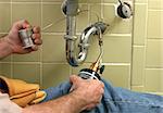 A plumber using a welding torch to solder pipe in the bathroom.