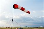 A red and white windsock flying in the wind to signal direction on an airfield