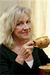 A beautiful mature woman enjoying a cup of coffee.  Soft focus applied.