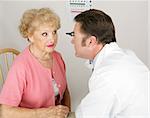 Optician looking into a senior woman's eyes during a routine eye exam.