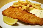 Fish and chips on a white plate with tartar sauce