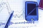 PDA and pen on Forex chart in blue lighting