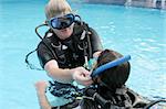 Scuba diving instructor demonstates a skill to a student in a swimming pool.