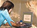 Young woman doing an online credit card payment in a rocky environment.