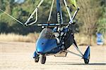 Blue microlight airplane on a dirt airfield