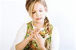 Studio portrait of a young blond girl who is examining her painted easter egg