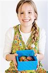 Studio portrait of a young blond girl who is presenting a blue box with her painted easter eggs