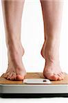 A pair of female feet standing on tip toe on a bathroom scale