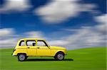 Yellow classic car at high speed in a green meadow (motion effect)