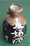 Decorated bottle of sake on green background