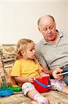 Grandpa and grand-daughter reading and playing