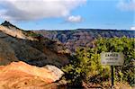 Danger sign warns visitors to stay away from edge of canyon land.  Waimea Canyon stretches beyond sign in deep ravines and crevices.