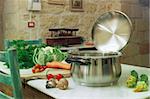 a stainless steel pot on the table with vegetable around