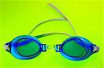 Pair of blue swimming goggles on an lime green background