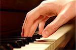 A Caucasian male's hand playing a piano in dramatic lighting