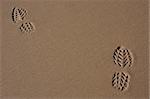 Two footprints on the sand of a beach