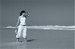 Beautiful woman on the beach with a starfish on the hand observing something (toned in PS)