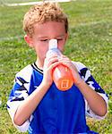 Young sweaty red faced boy taking drink at halftime of soccer game