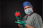 A cardiologist holding a patients heart in his hand.