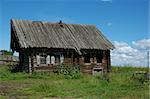 Single destroyed wooden house in field with old wooden draw-well