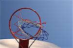 A tattered basketball goal outside on a sunny day.