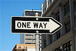 One way road city sign on a blue sky and buildings background