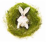 Easter toy white rabbit in a nest from a green grass on a white background