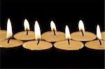 close up on two rows of candles on dark background