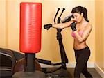Attractive woman kickboxing with red punching bag
