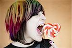 Alternative Girl Taking a Big Bite out of a Heart Lollipop