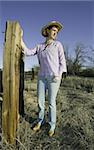 Woman wearing a cowboy hat in a rural setting.