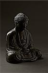 dramatically back-lit low-key image of The Buddha sitting in meditation; differential focus; tinted image