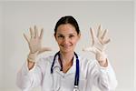 Young female doctor holding her gloved hands out and smiling playfully