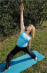 Beautiful sixty year old woman in a natural setting, doing the upward warrior asana in yoga.