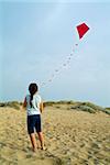 girl on beach playing with a red kite