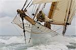Close up on the bow of a classic sailboat breaking through a wave