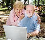 Senior couple enjoys using their computer outdoors.