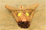 bikini girl doing Yoga exercise lying on the beach