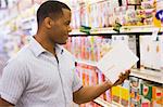 Man shopping in supermarket checking contents of packet