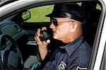 Police officer in squad car talking on his radio.  Closeup view.