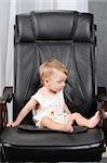 Very important small kid sits on real boss leather chair