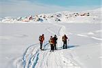 People on snow-shoes with inuit village in background