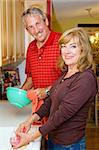 Beautiful mature couple sharing the household chores, doing dishes together.