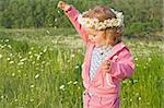 Little girl scattering daisy petals outdoors in the green field