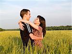 Teen couple embracing in field looking on each other