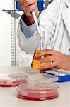 A chemist using a pipette and erlenmeyer flask in a laboratory.