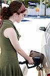 Young woman filling the gas tank of her automobile.