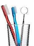 Two toothbrush and a mouth mirror in a glass.