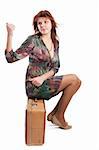 Female sitting on an old suitcase and hitching a lift